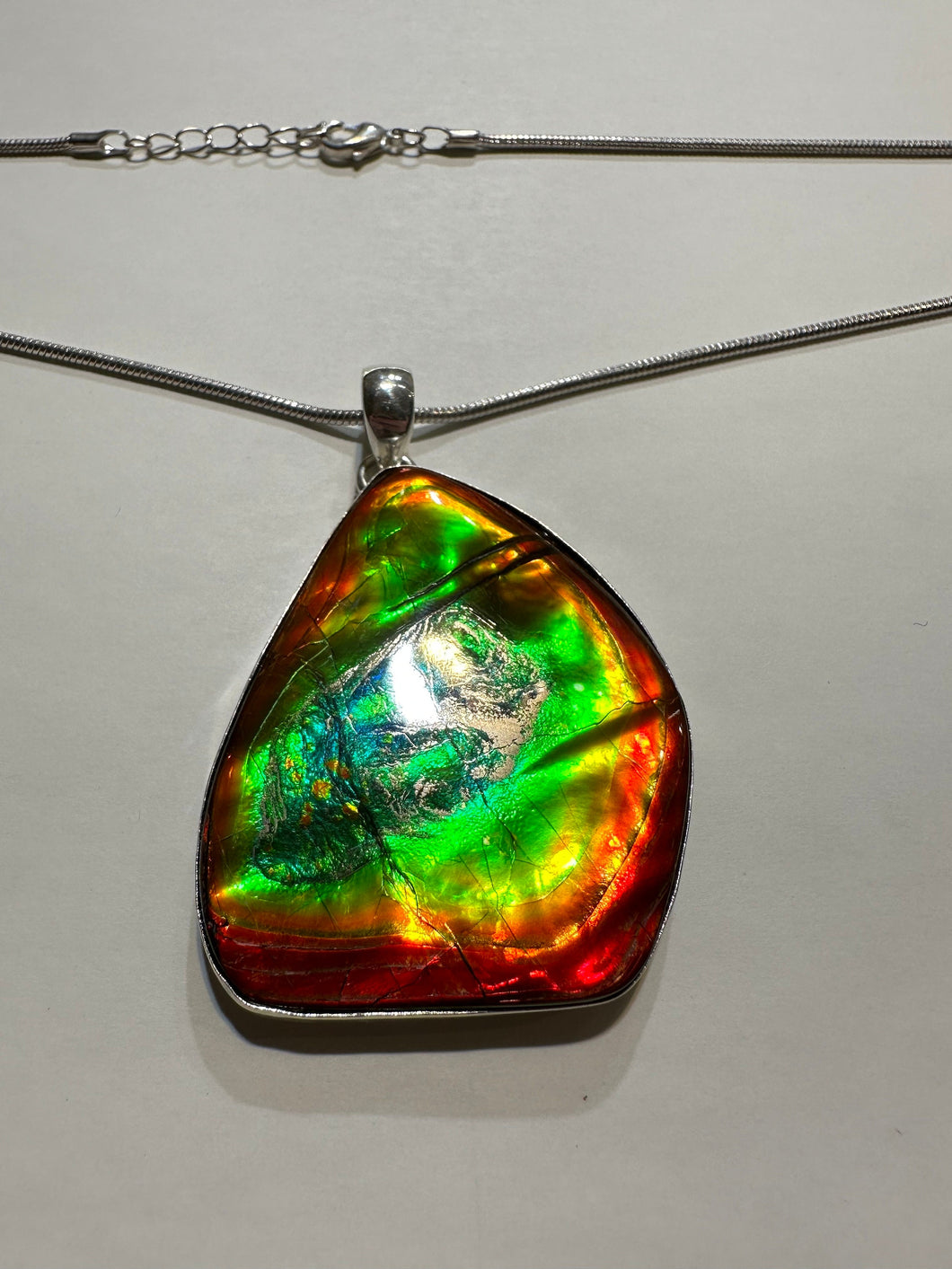 Beautiful ammolite necklace set in silver, featuring vibrant reds, yellows and blues